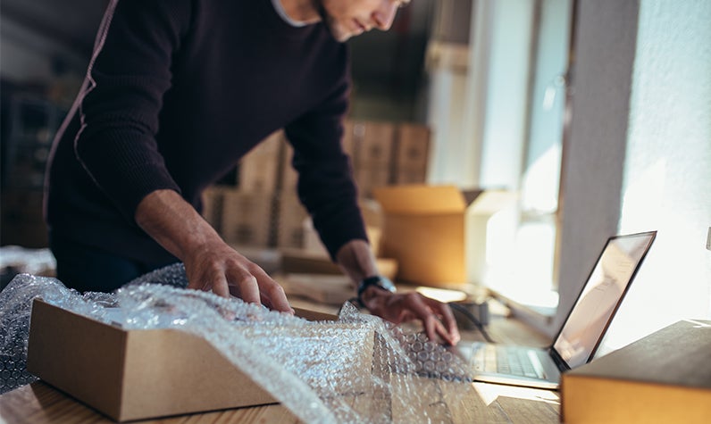 A man unpacking while looking up information on a laptop. 