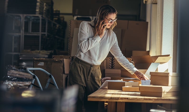 A woman on a phone packing her house for a move.