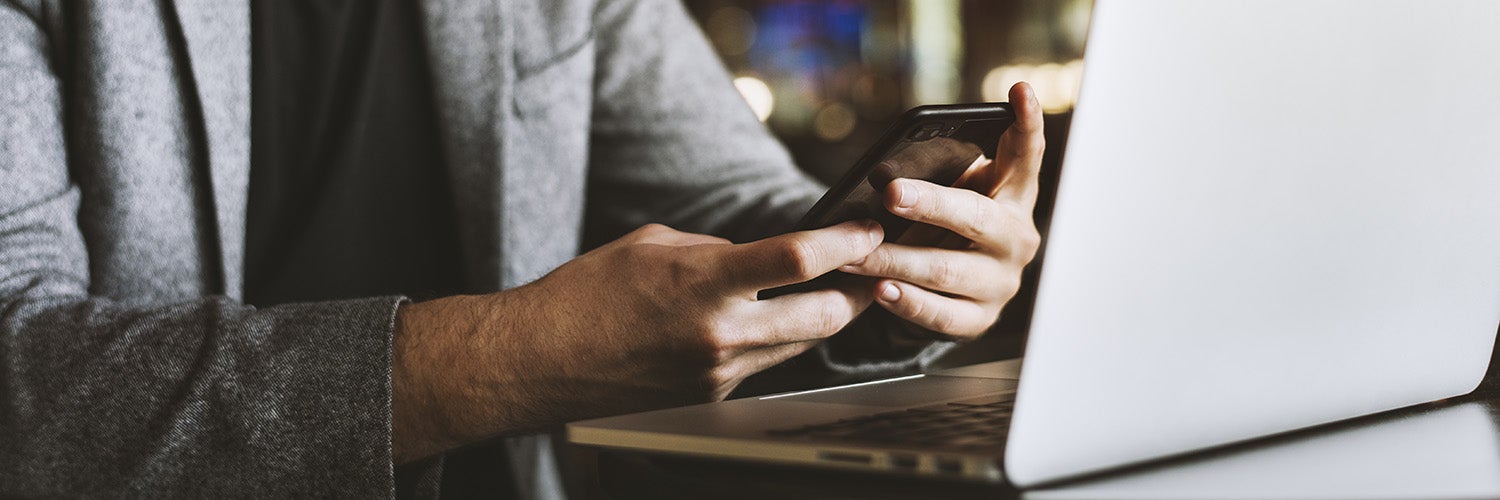 A man working on his phone and laptop.