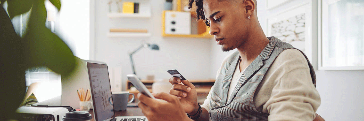 A man looks at his credit card and phone.