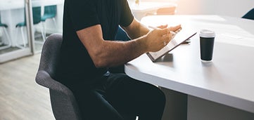 man sits at table writing on paper