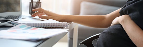 person sits in front of desk and paperwork