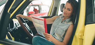 Person sits in vehicle looking at contract